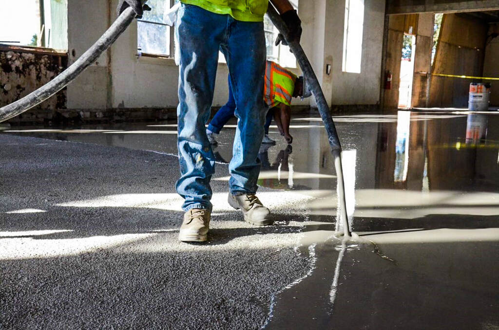 Master with roller for new screed concrete with self leveling cement mortar for floors. Concept building renovation home. 